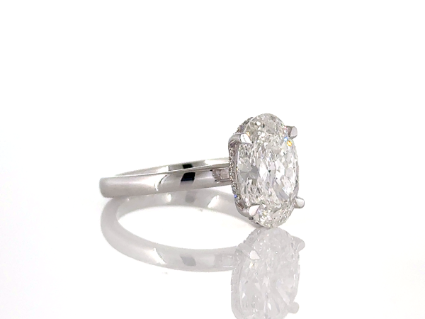Oval cut ring with hidden halo set in diamond studded claws